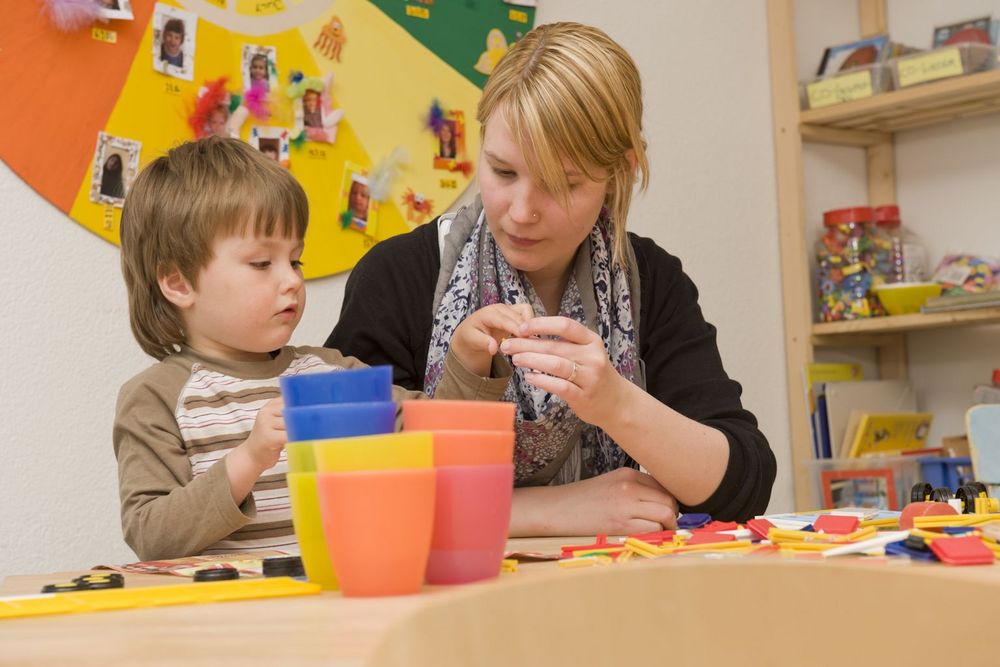 Kita-Mitarbeiterin spielt mit Kind